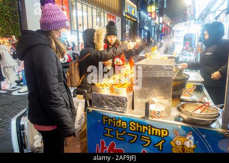 Seoul, Corea del Sud - 6 Dicembre 2019: a Myeongdong district a sera, il popolare sito per trattamenti estetici e di bellezza e negozi di cibo di strada. Foto Stock