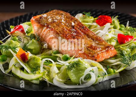 Filetto di fresco salmone alla griglia filetto di pesce con avocado e insalata fennal su una piastra nera. Foto Stock