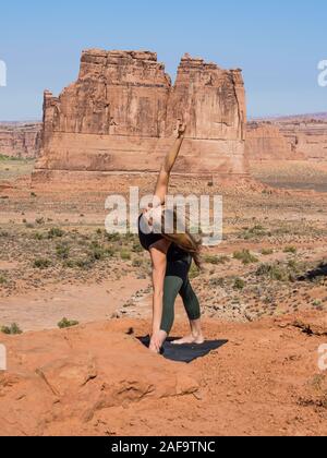 Un attraente giovane donna le pratiche yoga presso La Sal Mountains si affacciano nel Parco Nazionale di Arches nei pressi di Moab, Utah. Foto Stock