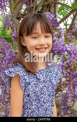 7 anno vecchia ragazza in piedi sotto un albero wysteria in Honfleur, Francia Foto Stock