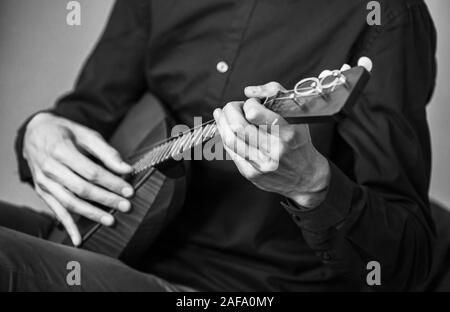 Le mani di un uomo giocando balalaika, close-up foto con messa a fuoco selettiva e motion blur effetto. Retrò stilizzata foto in bianco e nero Foto Stock