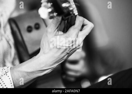 Musica dal vivo dello sfondo. Mano forte di una chitarra acustica player. Retrò stilizzata foto in bianco e nero con il fuoco selettivo Foto Stock