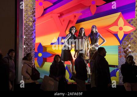 La gente in coda per entrare in un negozio la visualizzazione womens designer di lusso su capi di abbigliamento manichini nella sua finestra, sugli Champs Elysees di Parigi Foto Stock