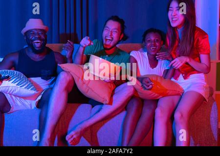 Gruppo di amici divertendosi a casa a guardare il calcio e il film sul televisore. godendo e celebrare insieme Foto Stock
