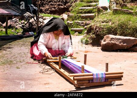 Taquile, Perù - Jan 5, 2019 :donna in abiti tradizionali rende tessere su la rottura a Taquile isola del lago Titicaca in Perù. Foto Stock