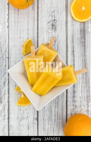Orange Popsicles (messa a fuoco selettiva; close-up shot) su un sfondo vintage Foto Stock