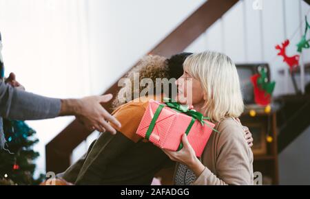Figlia dà dono e abbracciando l'anziana madre in vacanza Foto Stock