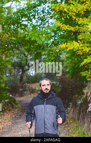 Uomo maturo con smartwatch facendo trekking in campo Foto Stock