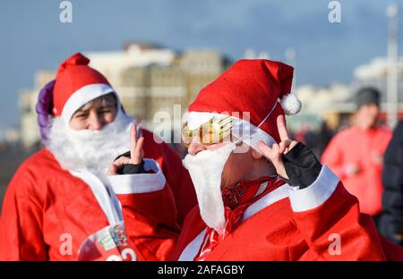 Brighton Regno Unito 14 Dicembre 2019 - centinaia tra cui bambini e cani prendere parte al Brighton Santa Dash in una giornata di vento lungo il lungomare aiutando a raccogliere fondi per la Rockinghorse la carità che è il braccio di raccolta fondi della Royal Alexandra ospedale per bambini . Credito: Simon Dack / Alamy Live News Foto Stock