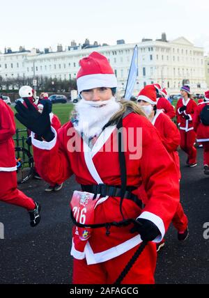 Brighton Regno Unito 14 Dicembre 2019 - centinaia tra cui bambini e cani prendere parte al Brighton Santa Dash in una giornata di vento lungo il lungomare aiutando a raccogliere fondi per la Rockinghorse la carità che è il braccio di raccolta fondi della Royal Alexandra ospedale per bambini . Credito: Simon Dack / Alamy Live News Foto Stock