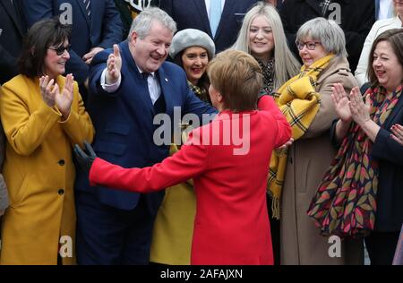 Primo Ministro Nicola Storione abbracci SNP Westminster leader Ian Blackford (seconda a sinistra) come lei si unisce SNP neoeletto MPs per una foto di gruppo chiamata al di fuori del V&un museo di Dundee. Foto Stock