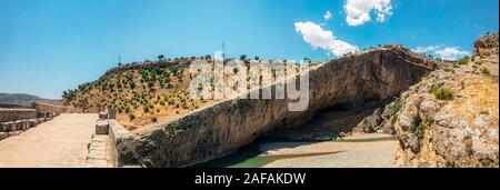 Vista panoramica del Ponte Severan, Cendere Koprusu è un fine ponte romano, vicino a Nemrut Dagi, Turchia. Strada fiancheggiata da colonne antiche Foto Stock