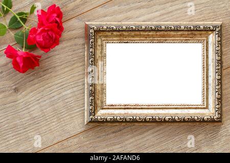 Marrone Vintage photo frame con copia spazio e red rose fiori su tavole di legno. Vista dall'alto. Foto Stock