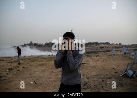 Dicembre 13, 2019: Gaza, Palestina. Il 13 dicembre 2019. Dimostranti palestinesi scontro con le forze israeliane ad est del Bereij al campo di rifugiati nella zona centrale della striscia di Gaza, durante questo venerdì una Grande Marcia di protesta di ritorno. I dimostranti avevano raccolto lungo il confine, con alcuni che lanciano pietre verso i soldati israeliani di stanza sull'altro lato della recinzione di separazione. Le forze israeliane hanno sparato gas lacrimogeni e proiettili a manifestanti, ferendo un certo numero di essi. Il grande marzo di restituire le proteste hanno avuto inizio presso la frontiera Gaza il 30 marzo 2018 a chiamata per il sollevamento del blocco israeliano su Foto Stock