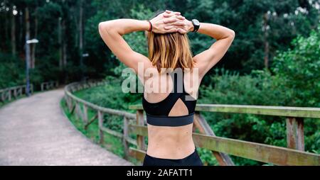 Irriconoscibile sportive facendo bracci di estensione all'aperto Foto Stock