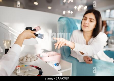 Donna scelta di smalto per unghie nel salone di bellezza Foto Stock