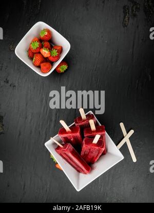 In casa Strawberry Popsicles (close-up shot; messa a fuoco selettiva) su sfondo vintage Foto Stock