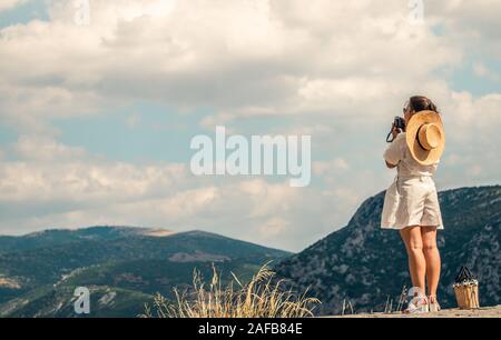 Giovane donna di moda vestire, scattare foto di Delfi paesaggio di montagna in Delphi, Grecia Foto Stock