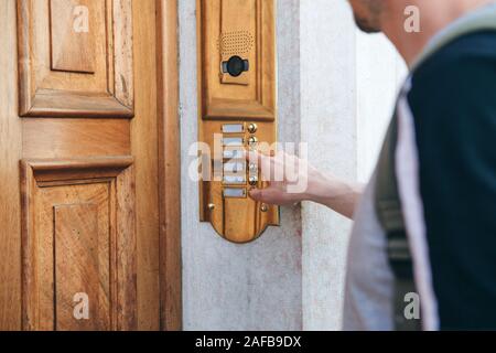 Close-up mano umana squilla il citofono per accedere all'interno della casa. Foto Stock
