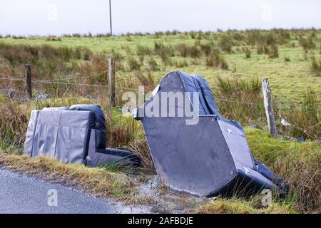 Volare il ribaltamento del divano di mobili sedie in strada in area rurale provocando inquinamento di campagna Foto Stock