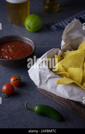 Fotografia di cibo di una scatola con nachos o tortilla chips con salsa guacamole e dip e di birra messicana o cerveza Foto Stock