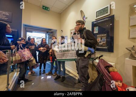 Londra, Regno Unito. Xiv Dic, 2019. Sciopero di terra a sud di Londra, un piccolo gruppo di anti-capitalista e anti-imperialisti contro la distruzione ambientale protesta all'interno di Barclays Bank che il carburante la crisi climatica. Sono andato a protestare quindi al di fuori di negozi compresi quelli che vendono i telefoni cellulari utilizzando i minerali che sono causa di guerra e di sfruttamento in Africa centrale, per la vendita di carni bovine provenienti da ranches distruggendo la foresta amazzonica, fast fashion prodotti e olio di palma prodotti. Credito: Peter Marshall / Alamy Live News Foto Stock