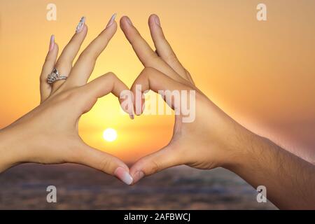 Coppia romantica in gesti di amore un cuore con le dita sul tramonto . formatura a mano a forma di cuore con il tramonto del sole silhouette . silhouette a forma di cuore con Foto Stock
