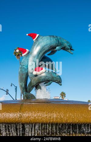 Scultura di tre delfini in bronzo che indossa il bianco e il rosso cappelli di Babbo Natale per la stagione di Natale all'entrata di Stearn's Wharf a Santa Barbara, CA. Foto Stock