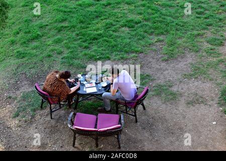 Guardando da sopra a due persone mangiare fuori nel parco a tavola. Ella usando il telefono per fotografare tazza da caffè, Rovigno Croazia Foto Stock