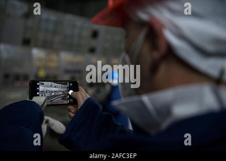 Un visitatore di scattare una foto all'interno della sala di controllo della centrale di Chernobyl il reattore 4, il sito di tutto il mondo più devastante catastrofe nucleare. L'ex centrale nucleare della sala di controllo è dove ingegneri spegnere il reattore di pompe di raffreddamento come parte di un test di sicurezza nel mese di aprile del 1986, che ha portato ad una esplosione che ha ucciso almeno 28 persone nelle immediate conseguenze e contaminato la zona circostante. La camera si trova al di sotto di una 36.000 tonnellate di contenimento in acciaio arch, ha ancora il suo originale le schermate del display e pannelli di pulsanti di comando. Chernobyl, Ivankiv Raion, Oblast di Kiev, Ucraina, Europa Foto Stock