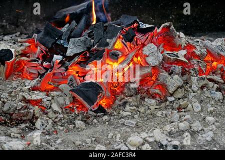 Un mucchio di legna brucia in mezzo alla cenere-superficie coperta, close-up Foto Stock