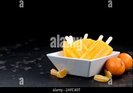 Porzione di freschi fatti in casa Popsicles mandarino (close-up shot; messa a fuoco selettiva) su un sfondo vintage Foto Stock