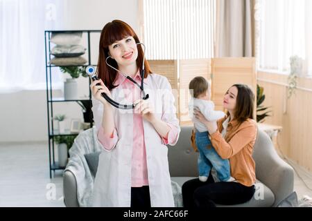 Bambina con la sua madre ad un medico su consultazione. Sorridenti femmine giovane medico in bianco velo uniforme e stetoscopio. Foto Stock