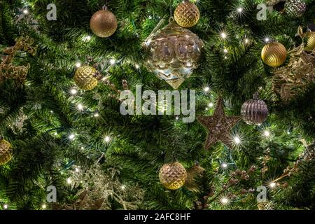 Dettagli di un albero di Natale con rami di albero appeso con una palla e stelle di ornamenti, nastri e giocattoli di Natale. Il concetto della tradizionale celebrazione. Foto Stock