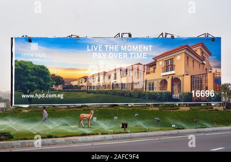 Poster gigante sul ciglio della strada del 6th.Ottobre città satellite appena al di fuori de Il Cairo annuncia l'acquisto di nuove case per persone ricche. Il Cairo, Egitto Foto Stock