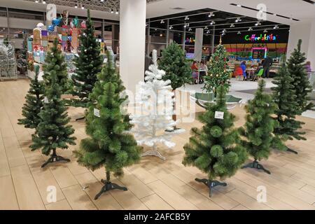 Artificiale di alberi di Natale di diversi colori e dimensioni per la vendita in un supermercato. Una vasta scelta di alberi di Natale per il nuovo anno. Foto Stock