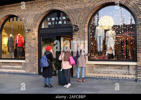 Giovani donne lo shopping di Natale in piedi all'ingresso del negozio designer Twin a gocce di carbone cantiere Kings Cross Londra Inghilterra KATHY DEWITT Foto Stock