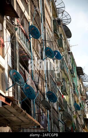 Vecchia facciata di edificio con molte parabole satellitari, Yangon, Myanmar Foto Stock