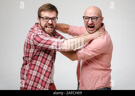 Due uomini in bicchieri soffocare ogni altra, guardano furiosamente la fotocamera, grin i loro denti e urlare. Foto Stock