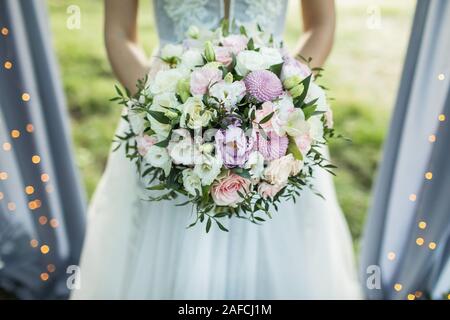 Sposa tenendo nelle mani di piccoli Bouquet nozze in colori pastello. La luce rosa e rose bianche, crisantemo e viola peonia. Foto Stock