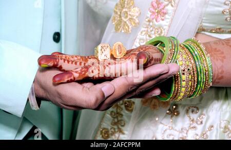 Un indiano si sposa e lo sposo tenendo le mani con anello durante un Indù rituale di nozze Foto Stock