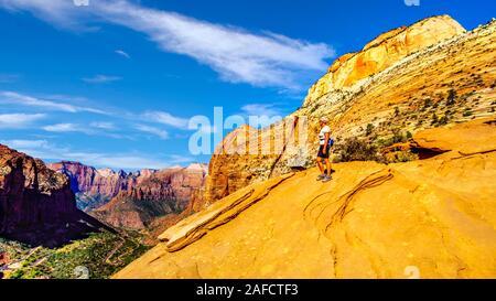 Attiva donna Senior cercando in Canyon Zion dalla sommità del Canyon Overlook Trail nel Parco Nazionale di Zion, Utah, Stati Uniti Foto Stock