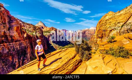 Attiva donna Senior di godere della vista delle montagne che circondano il canyon Zion dalla sommità del Canyon Overlook Trail nel Parco Nazionale di Zion, Utah, Foto Stock