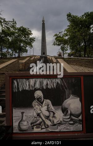 National Heroes Acre, Harare, Zimbabwe. Un dipinto di una donna in abiti tradizionali che fa vasi e vasi di argilla serve come una barriera makeshift per bloccare la scala al monumento in cima alla Heroes Acre, come i monumenti ha bisogno di riparazioni e il paese sta attraversando una crisi finanziaria. Novembre 2019. Foto Stock