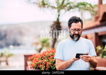 Tipo di uomo su di un moderno telefono cellulare nel dispositivo esterno di attività per il tempo libero con la tecnologia - Ritratto di età compresa tra i pazienti adulti con sfondo sfocato Foto Stock