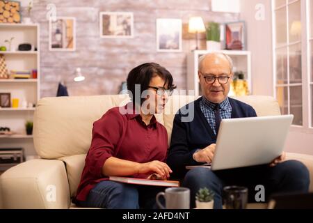 Nonna e nonno usando un computer portatile per chattare con i loro nipoti. Le persone anziane usando tecnologie moderne Foto Stock