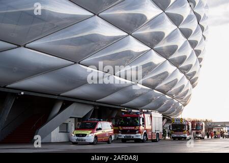 Monaco di Baviera, Germania. 15 Dic, 2019. Veicoli di emergenza dei vigili del fuoco sono in piedi nella parte anteriore della Allianz Arena durante un disastro esercizio di controllo per il Campionato Europeo di Calcio 2020. Durante l'esercizio, l'esplosione di una friggitrice in uno snack bar all'interno dell'arena è stato simulato con un attacco in massa di persone ferite. Il giunto di comando di emergenza esercizio "EMÜ19' di vigili del fuoco, polizia, servizi di salvataggio, la città di Monaco di Baviera e il tedesco Football Association serve a preparare per la UEFA Campionato Europeo 2020. Credito: Matthias esitano di fronte/dpa/Alamy Live News Foto Stock