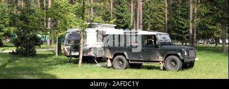 Un vecchio caravan con un veicolo fuoristrada nella foresta Foto Stock