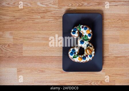 festa di famiglia con una torta in forma di numero tre. Vista dall'alto Foto Stock