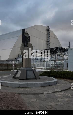 Il monumento al Chernobyl liquidatori (che una volta costruito il vecchio sarcophagos) nella parte anteriore del nuovo confinamento sicuro nella sua posizione finale. Il nuovo rifugio è una struttura costruita per confinare i resti del numero 4 unità di reattore presso la centrale nucleare di Cernobyl, in Ucraina, che è stato distrutto durante la catastrofe di Chernobyl nel 1986.centrale nucleare di Cernobyl Chernobyl Ivankiv Raion, Oblast di Kiev, Ucraina, Europa Foto Stock